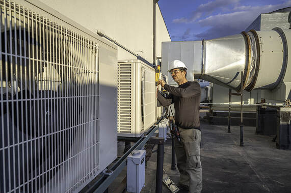 An HVAC technician in Greenwich, CT, performs air conditioning maintenance.